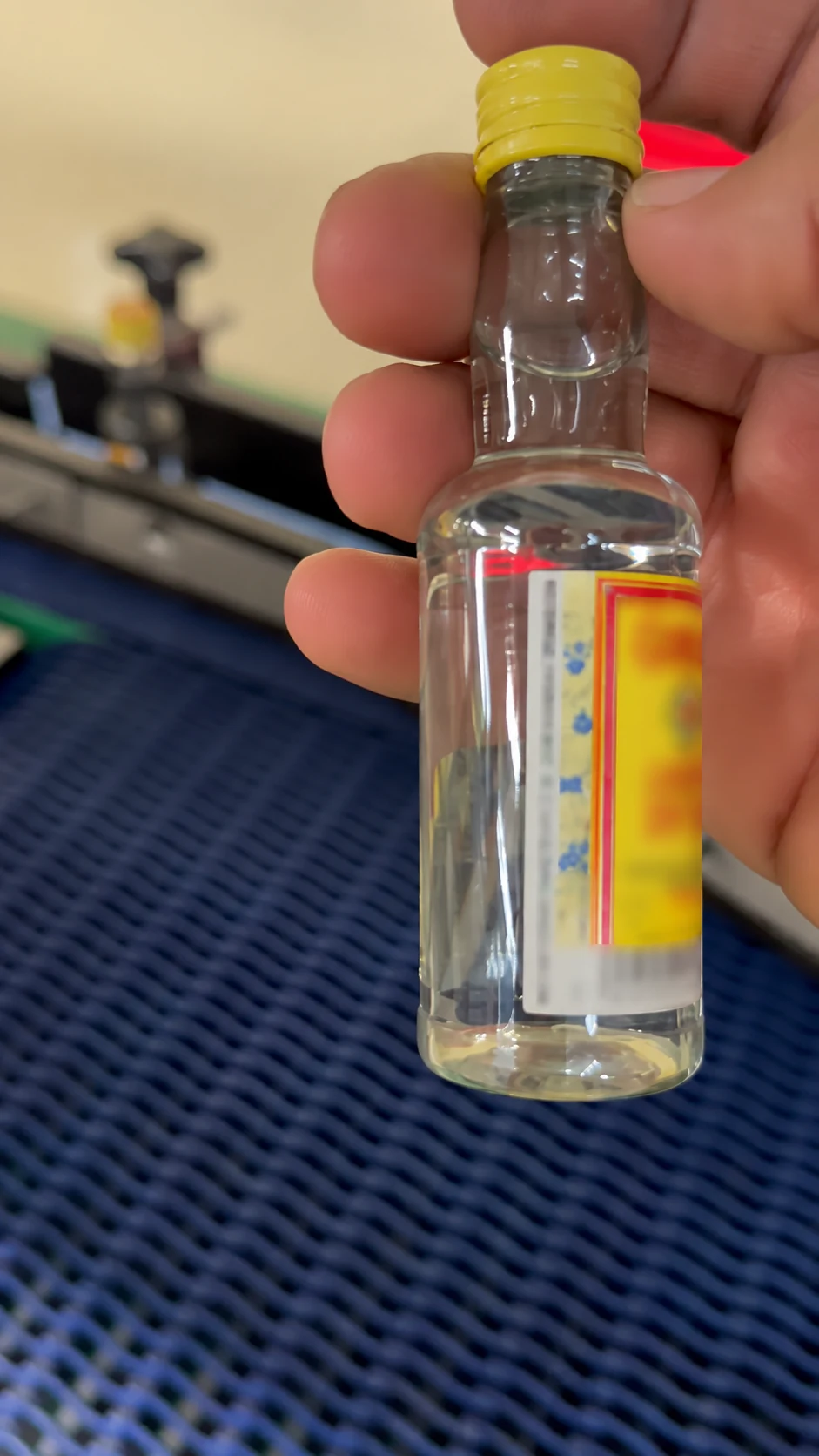Small glass bottle with a wrap-around label applied by the standalone labeller
